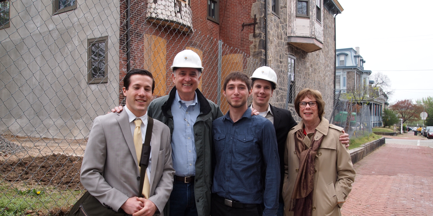 Picture of DSH alumni in front of house under construction